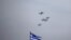 FILE - A Greek national flag flutters as a formation of fighter jets fly over Athens, Greece, April 4, 2017. Israel and Greece on Sunday signed their biggest ever defense procurement deal.