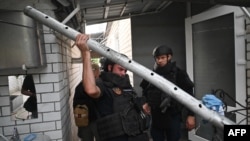 Ukrainian explosive experts carry a fragment of a cluster missile that damaged a house after a Russian strike on the small town of Derhachi, in Ukraine's Kharkiv region, Sept. 8, 2024.