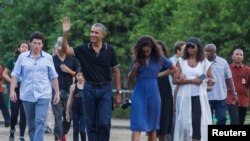 Mantan Presiden AS, Barack Obama, melambaikan tangan saat berjalan bersama putrinya, Mali, dan istrinya Michelle selama kunjungan ke Candi yang berasal dari abad ke-9, Borobudur, di Magelang, Indonesia tanggal 28 Juni 2017 (foto: REUTERS/Pius Erlangga) 