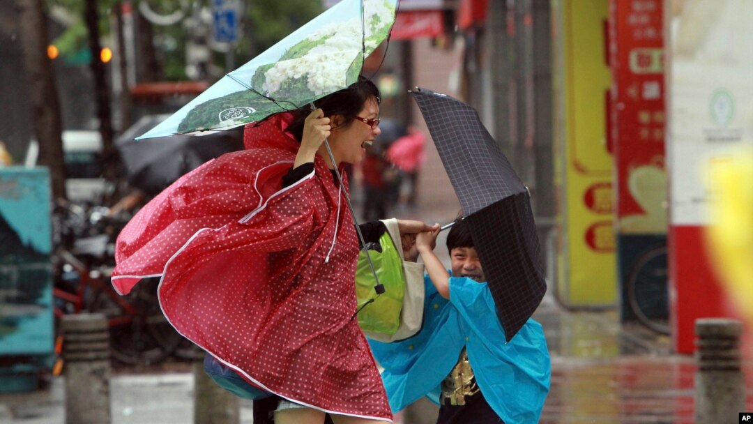 Seorang perempuan dan anaknya memegang payung mereka dengan erat, saat angin kencang yang dipicu oleh topan Usagi bergerak mendekati Taipei, Taiwan (21/9).