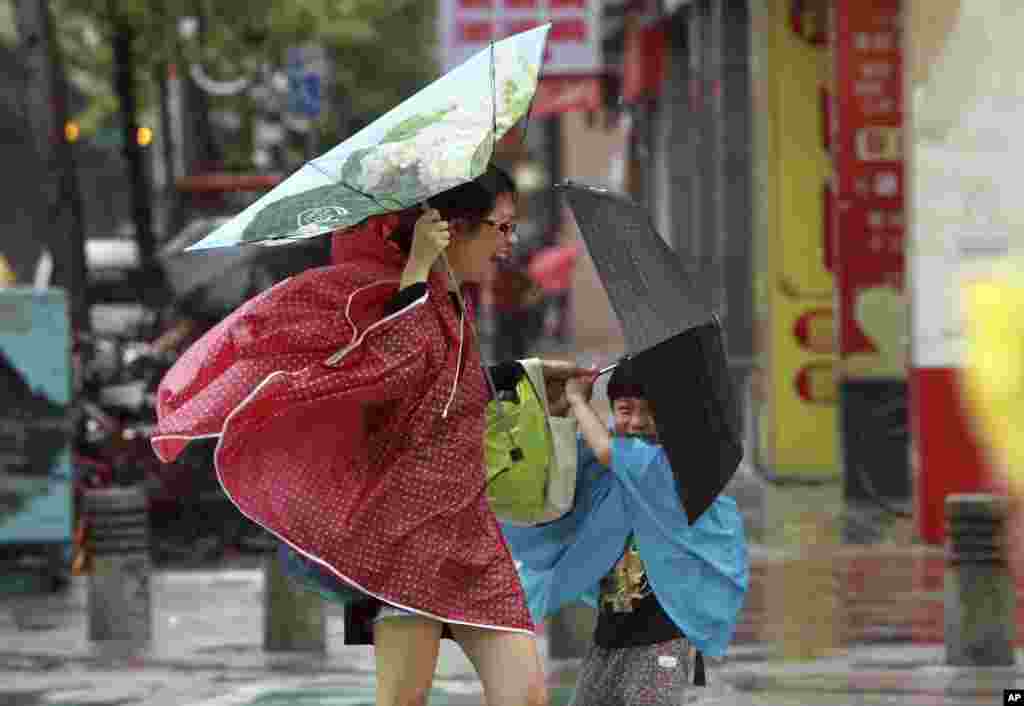 Seorang perempuan dan anaknya memegang payung mereka erat-erat di tengah angin kencang yang dibawa Topan Usagi di Taipei, Taiwan (21/9).