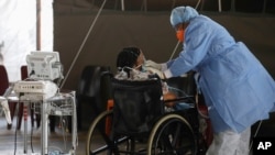 ARCHIVO - Un trabajador de la salud con equipo de protección personal (EPP) suministra oxígeno a un paciente en la sala temporal dedicada al tratamiento de posibles pacientes con coronavirus COVID-19 en el Hospital Académico Steve Biko en Pretoria, Sudáfrica.