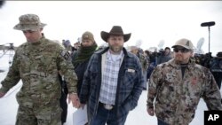 Ammon Bundy, tengah, salah satu anak peternak Nevada, Cliven Bundy, berjalan setelah berbicara dengan wartawan di kantor pusat Malheur National Wildlife Refuge, 4 Januari 2016, dekat Burns, Oregon.