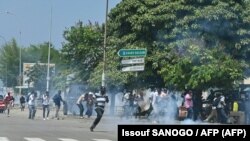 Des partisans de l'ancien président ivoirien Laurent Gbagbo affrontent la police anti-émeute à Abidjan, le 17 juin 2021, avant son arrivée dans le pays.