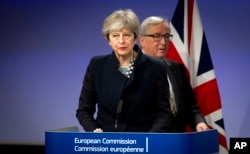 FILE - European Commission President Jean-Claude Juncker, right, walks behind British Prime Minister Theresa May prior to addressing a media conference at EU headquarters in Brussels, Dec. 4, 2017.