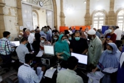 FILE - People gather for COVID-19 vaccine doses at a vaccination center in Karachi, Pakistan, March 22, 2021.