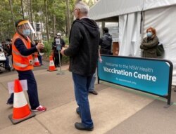 People wait outside a coronavirus disease (COVID-19) vaccination centre at Sydney Olympic Park in Sydney, Australia, July 14, 2021.