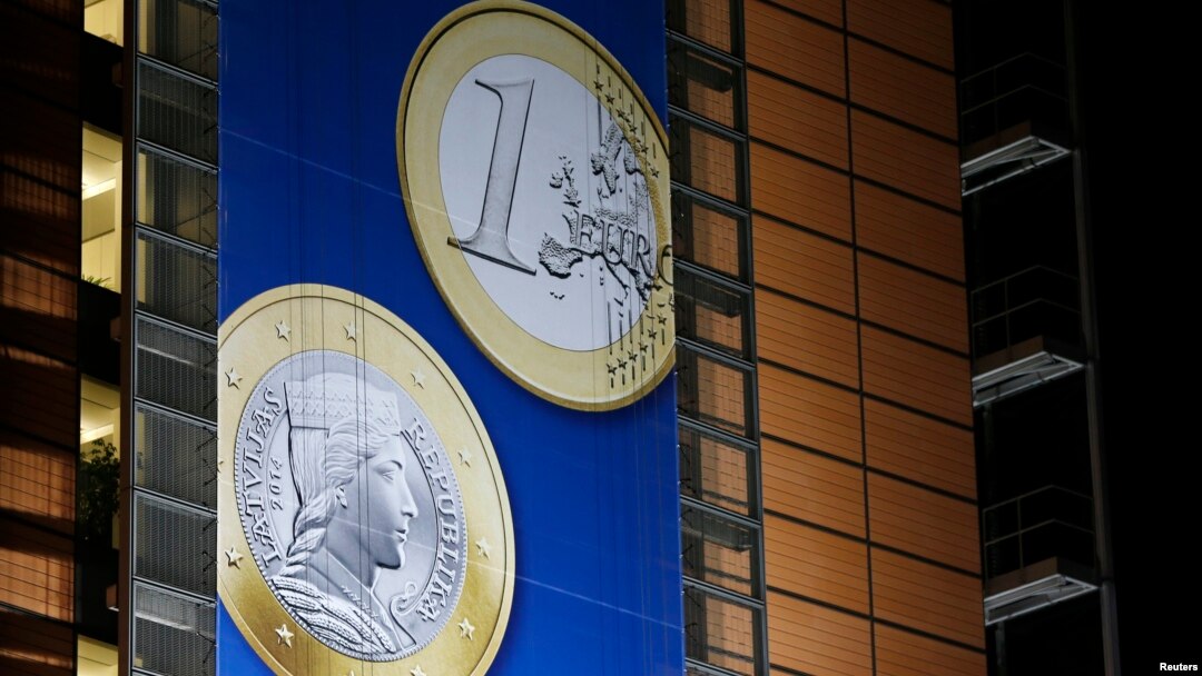 Spanduk yang menunjukkan gambar koin Euro Latvia dipasang di depan markas besar Komisi Eropa di Brussels (20/12). (Reuters/Francois Lenoir)