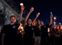 FILE - Attendees raise candles at a vigil for the victims of the shooting at Marjory Stoneman Douglas High School, Feb. 15, 2018, in Parkland, Fla.