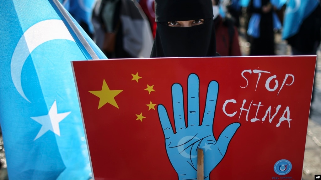资料照：在土耳其首都伊斯坦布尔的维吾尔人手举抗议中国的标语牌参加示威集会。（2021年3月25日）(photo:VOA)