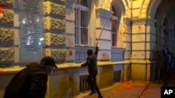 A protester breaks a window on the City Hall building during a protest in Novi Sad, Serbia, Nov. 5, 2024.