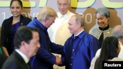 U.S. President Donald Trump and Russian President Vladimir Putin shake hands as they take part in a family photo at the APEC summit in Danang, Vietnam, Nov. 10, 2017.