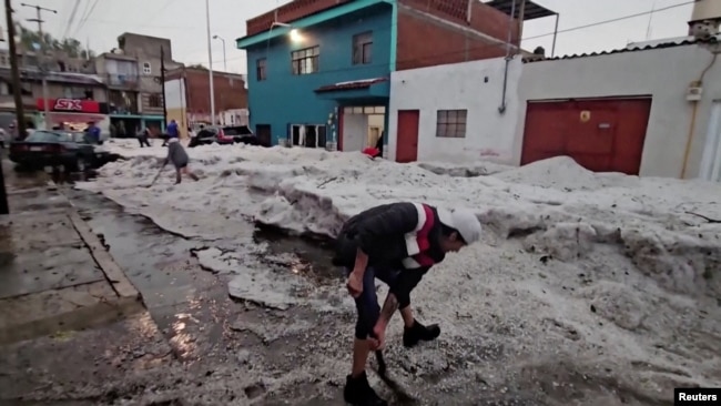 La gente quita el hielo grueso de una calle después de una tormenta de granizo en medio de una ola de calor, en Puebla, México, el 24 de mayo de 2024.