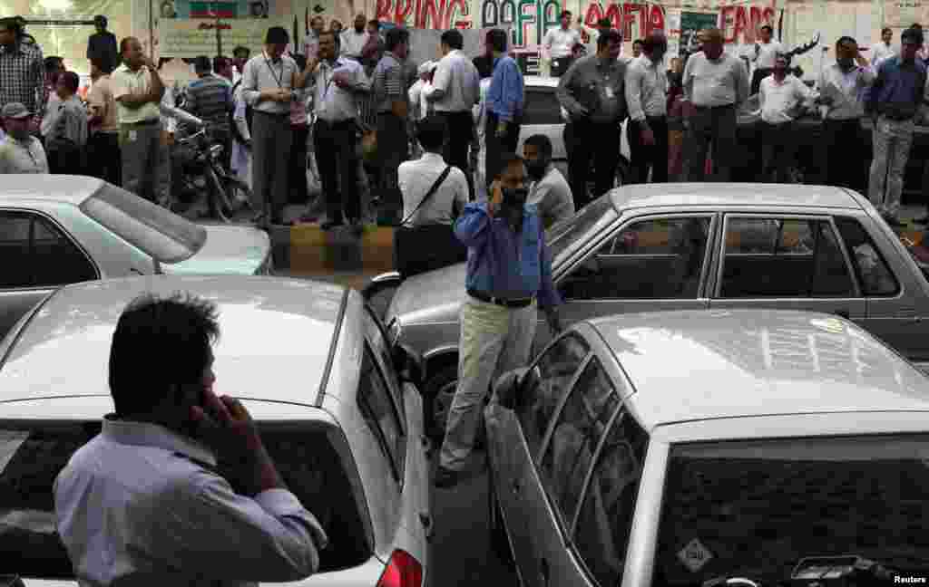 Office workers stand outside of their buildings following a tremor in Karachi, April 16, 2013. An 8.0 magnitude earthquake struck Iran on Tuesday with tremors felt across Pakistan among other regions, media reported.