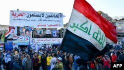 Iraquíes en Nasiriya enarbolan una bandera nacional durante una protesta para rechazar la nominación de Mohamed Alaui como primer ministro. Febrero 2 de 2020. Foto: AFP