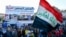 Iraquíes en Nasiriya enarbolan una bandera nacional durante una protesta para rechazar la nominación de Mohamed Alaui como primer ministro. Febrero 2 de 2020. Foto: AFP