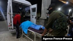 Indian police personnel carry the body of a street vendor who was shot dead by unidentified gunmen, at a hospital in Srinagar on Oct. 16, 2021.