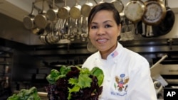 FILE - White House chef Cristeta Comerford holds produce in the kitchen of the White House in Washington.