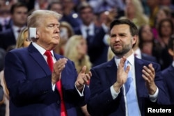 Republican presidential nominee and former U.S. President Donald Trump applauds with his choice for vice president, J.D. Vance, at the Republican National Convention at the Fiserv Forum in Milwaukee, July 15, 2024.