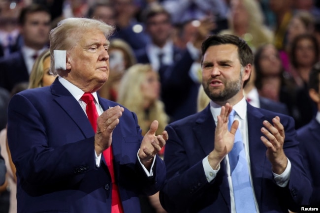 Republican presidential nominee and former U.S. President Donald Trump applauds with his choice for vice president, J.D. Vance, at the Republican National Convention at the Fiserv Forum in Milwaukee, July 15, 2024.