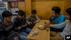 Para siswa Kashmir menjelajah internet melalui telepon genggam mereka, saat duduk di sebuah restoran di Srinagar, Kashmir yang dikuasai India, 26 April 2017. (Foto: dok).