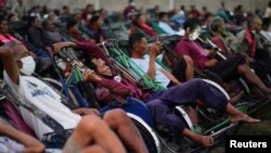 Tricycle drivers attend an outdoor movie screening held by a private organization, where cash and food donations are distributed to help them get by amid a tourism slump caused by the coronavirus disease (COVID-19) outbreak, in Phnom Penh, Cambodia, January 23, 2021. (REUTERS)