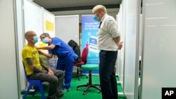 Britain's Prime Minister Boris Johnson, right, visits a vaccination hub in the Stoke Mandeville Stadium in Aylesbury, England, Jan. 3, 2022.