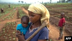 FILE - A woman and her child, who fled from rebel attacks, stand in a field, in Tshikapa, Kasai region, Democratic Republic of Congo, July 27, 2017.