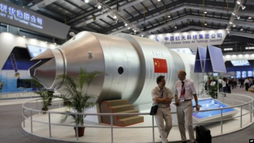 FILE - Visitors sit besides a model of China's Tiangong 1 space station at the 8th China International Aviation and Aerospace Exhibition in Zhuhai city, south China, in November 2010. Tiangong 2 will be sent into space Thursday.