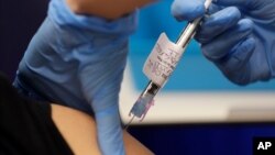 Seorang menerima suntikan kandidat vaksin Covid-19 yang sedang diuji klinis, di Imperial College, London, Inggris.