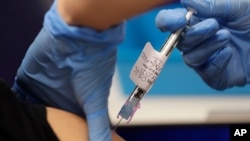 FILE - A volunteer is injected with a coronavirus vaccine as part of an Imperial College vaccine trial, at a clinic in London, Aug. 5, 2020.