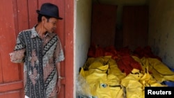 A villager stands near body bags containing the dead bodies of asylum seekers, who were killed when their boat sank, at an Agrabinta health clinic on the outskirts of Sukabumi, Indonesia's West Java province, Sept. 28, 2013.