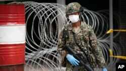 FILE - A solider stands guard in front of a barricaded building under lockdown, in downtown Kuala Lumpur, Malaysia, April 7, 2020.