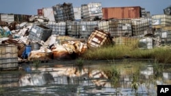 FILE - Containers used for hazardous chemicals lie exposed in a junkyard run by the Chinese-led Dar Petroleum Operating Co., near Paloch, South Sudan, Oct. 1, 2018. 