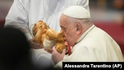 Pope Francis kisses the baby Jesus as he presides over an Epiphany mass in St.Peter's Basilica, at the Vatican, Monday, Jan. 6, 2025. 