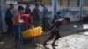 FILE - Palestinians collect clean drinking water at a desalination plant that now operates around the clock in Deir el-Balah, Gaza, a resource they barely have had any access to during the war, Nov. 14, 2024.