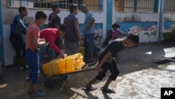 FILE - Palestinians collect clean drinking water at a desalination plant that now operates around the clock in Deir el-Balah, Gaza, a resource they barely have had any access to during the war, Nov. 14, 2024.