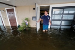 Rudy Horvath walks out of his home, a boathouse in the West End section of New Orleans, as it takes on water a from storm surge in Lake Pontchartrain in advance of Tropical Storm Cristobal, June 7, 2020.