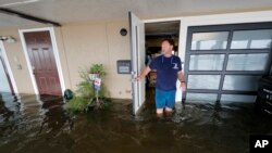 Rudy Horvath walks out of his home, a boathouse in the West End section of New Orleans, as it takes on water a from storm surge in Lake Pontchartrain in advance of Tropical Storm Cristobal, June 7, 2020.