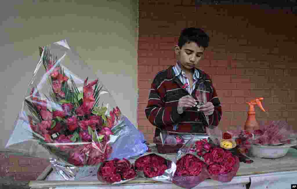 A boy prepares bouquets of flowers for sale on Valentine's Day while waiting for customers at a roadside stall in Faisalabad, Pakistan, February 14, 2012. (Reuters)
