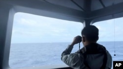 Badan Keamanan Laut menggunakan teropong untuk memantau pergerakan kapal penjaga pantai China di perairan Laut Natuna Utara di wilayah sengketa Laut China Selatan, Kamis, 24 Oktober 2024. (BAKAMLA via AP)