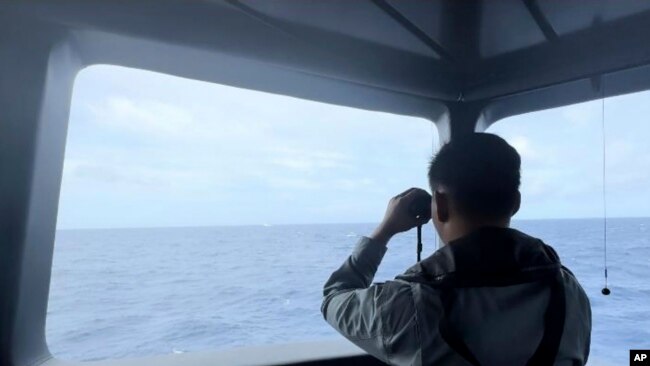 Anggota Badan Keamanan Laut (Bakamla) tampak menggunakan teropong untuk mengawasi pergerakan kapal penjaga pantai China di Laut Natuna Utara, pada 24 Oktober 2024. (Foto: Bakamla via AP)