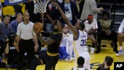 Lebron James de Cleveland Cavaliers, à gauche cherchant à marquer lors de la rencontre face à Golden State Warriors en NBA, le 12 juin 2017 (AP Photo/Ben Margot)