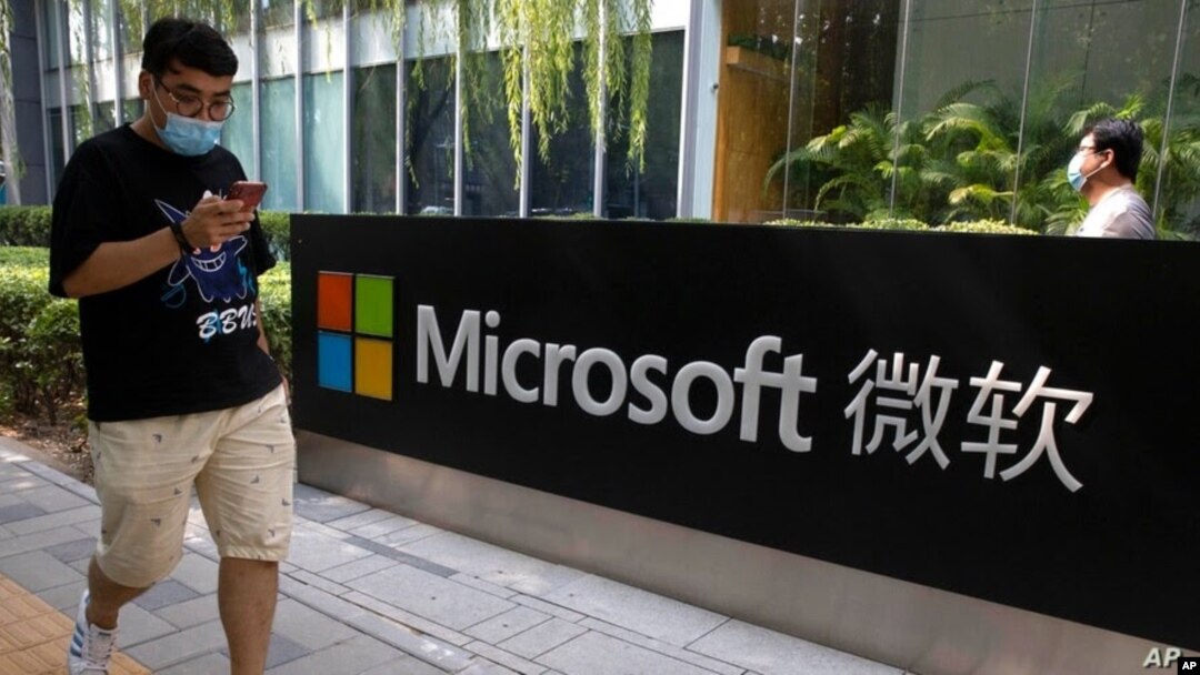 Un hombre mira su teléfono inteligente mientras camina por la oficina de Microsoft en Beijing, China, el 7 de agosto de 2020. 