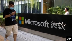 Un hombre mira su teléfono inteligente mientras camina por la oficina de Microsoft en Beijing, China, el 7 de agosto de 2020. 