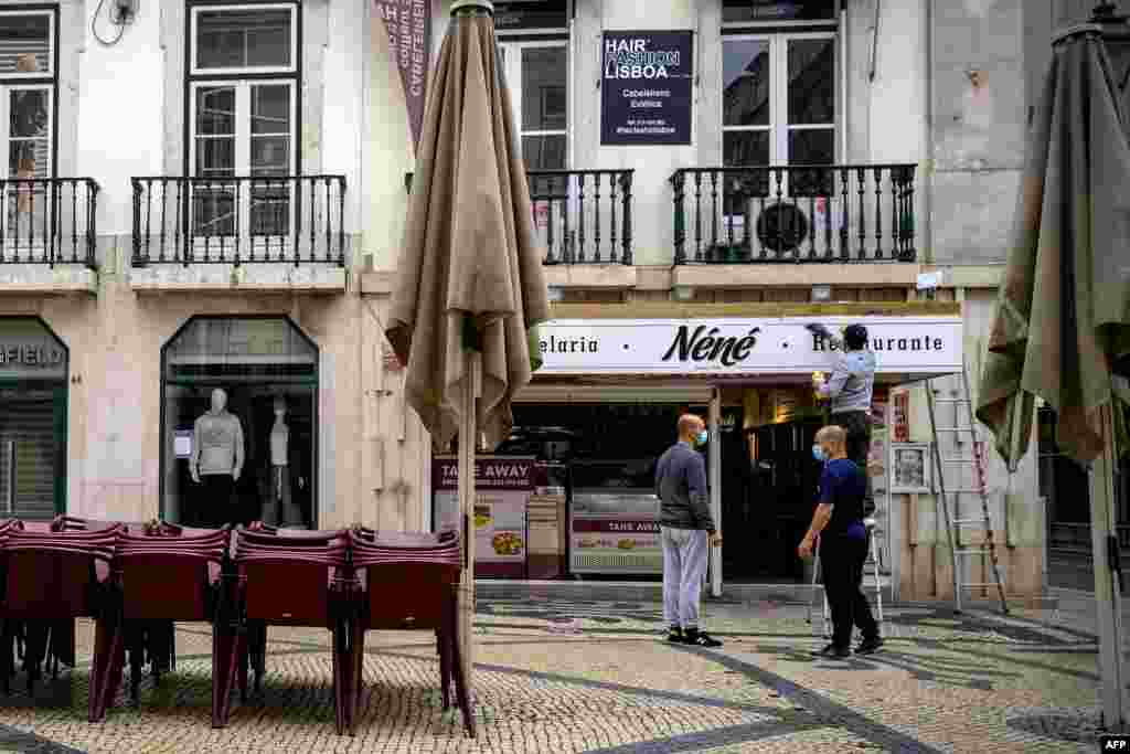 포르투갈 리스본의 한 식당 종업원이 간판을 닦고 있다. 포르투갈은 신종 코로나바이러스 확진자 감소로 방역 규제를 완화하고 있다. 