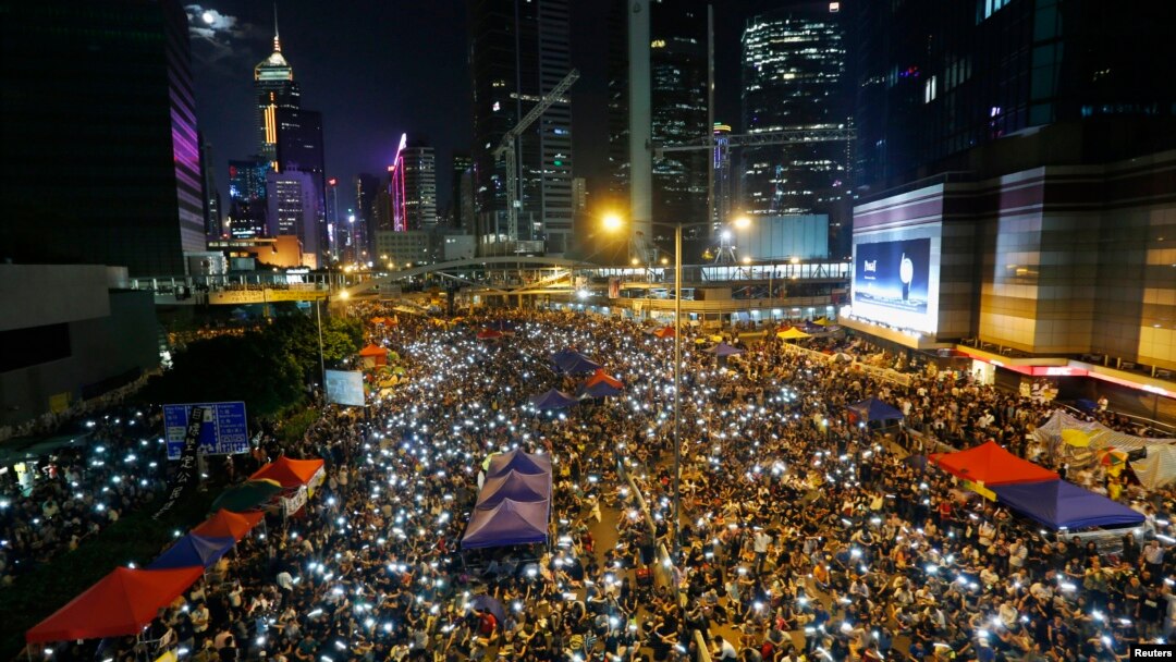 Para demonstran pro-demokrasi di Hongkong bernyanyi sambil melambaikan telepon genggam mereka dalam sebuah aksi protes di luar gedung pemerintah di Hong Kong (10/10).