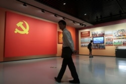 FILE - A man walks past a section featuring a Chinese Communist Party flag next to the party loyalty oath at an exhibition at the Museum of Contemporary Art and Planning Exhibition in Shenzhen, China, Dec. 4, 2018.