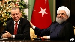 ARSIP - Presiden Iran, Hassan Rouhani, kanan, tertawa dalam sebuah konferensi pers gabungan dengan Presiden Turki, Recep Tayyip Erdogan, 4 Oktober 2017 (foto: Kayhan Ozer/Layanan Press Kantor Kepresidenan, Pool Photo via AP)