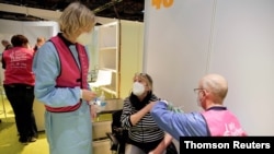 Una mujer es vacunada contra la enfermedad del coronavirus (COVID-19) en el centro de vacunación Treptow Arena en Berlín, Alemania. Diciembre 27 de 2020.